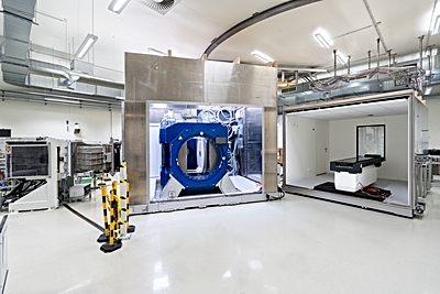 Foto: Beam line of the proton therapy system (left) with opened Aurora-PT system (i.e. in-beam MRI (middle) and patient couch (right)) ©Copyright: UKD/Kirsten Lassig